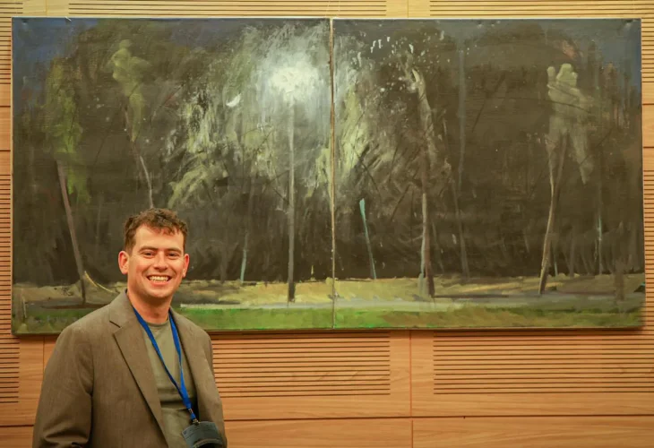 Matan Skopski with one of his paintings at the Knesset exhibition