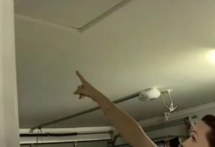 The homeowner points to the attic entrance where the intruder lived for weeks.