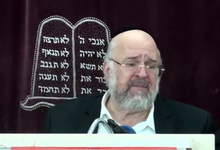 A photo of Rabbi Baruch Rosenbloom with the Ark Curtain and the Tablets of the Covenant behind him