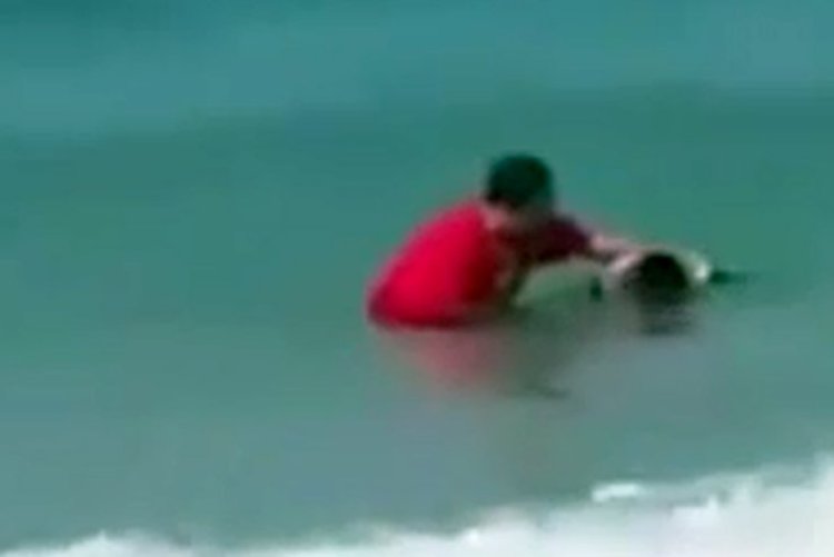 אחד הנערים בעת הטבלתו בים (צילום מסך)