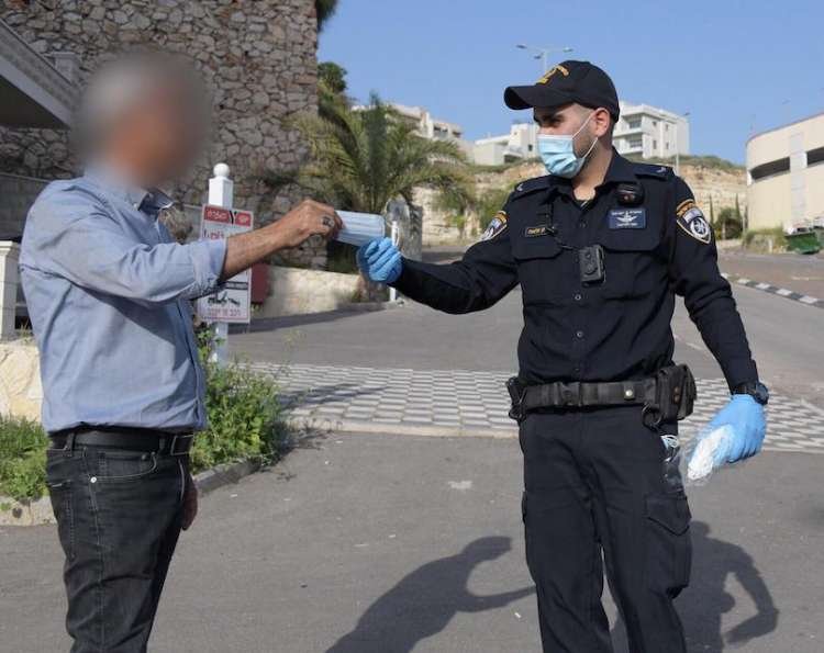 שוטר מחלק לאזרח מסכת מגן, אתמול (צילום: דוברות המשטרה)