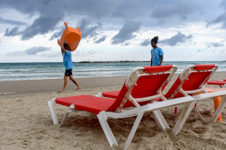עובדים מסדרים כסאות ושמשיות בחוף הים של תל אביב, בשבוע שעבר (צילום: פלאש 90)