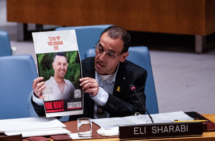 אלי שרעבי באו''ם, מציג את תמונתו של אחיו יוסי הי''ד, מרץ 2025 (לירי אגמי, פלאש 90)