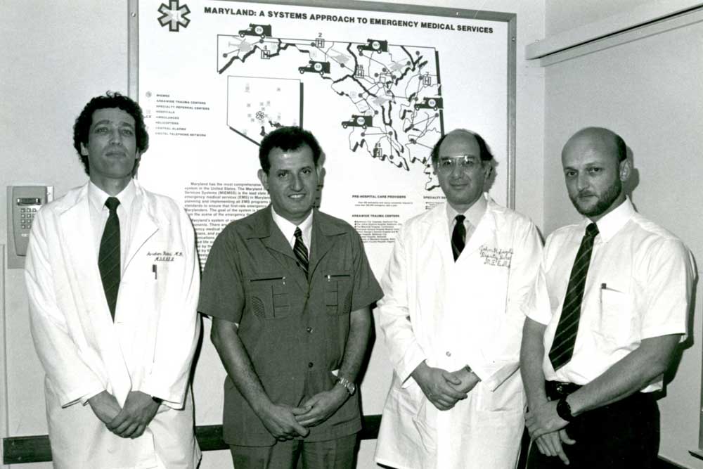 ביחידת שוק-טראומה בבולטימור, מרילנד ארה"ב. עומדים מימין לשמאל: אל"מ (מיל') ד"ר ברוך מרגנית, פרופ' ג'ון סיגל, תא"ל (מיל') פרופ' יהודה דנון ופרופ' אבי ריבקינד (קרדיט: אוסף פרטי, אבי ריבקינד)