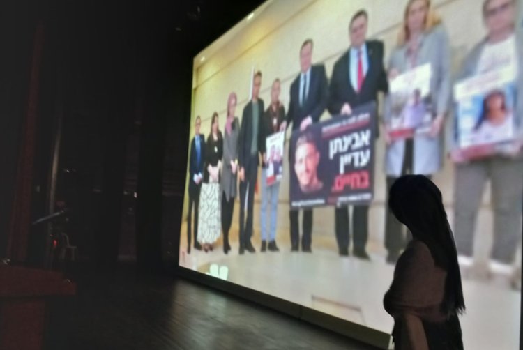 דיצה אור, אמו של אבינתן, על רקע תמונת בנה החטוף בעזה