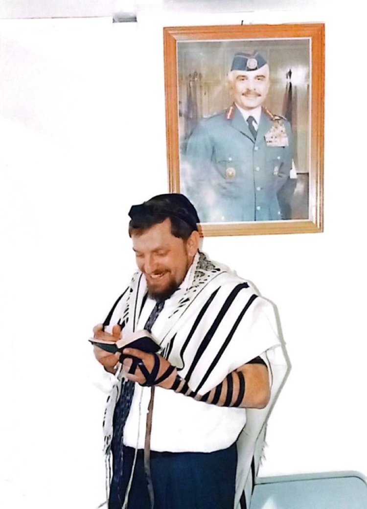 Leibovitz praying at the Aqaba crossing, with King Hussein's portrait in the background.